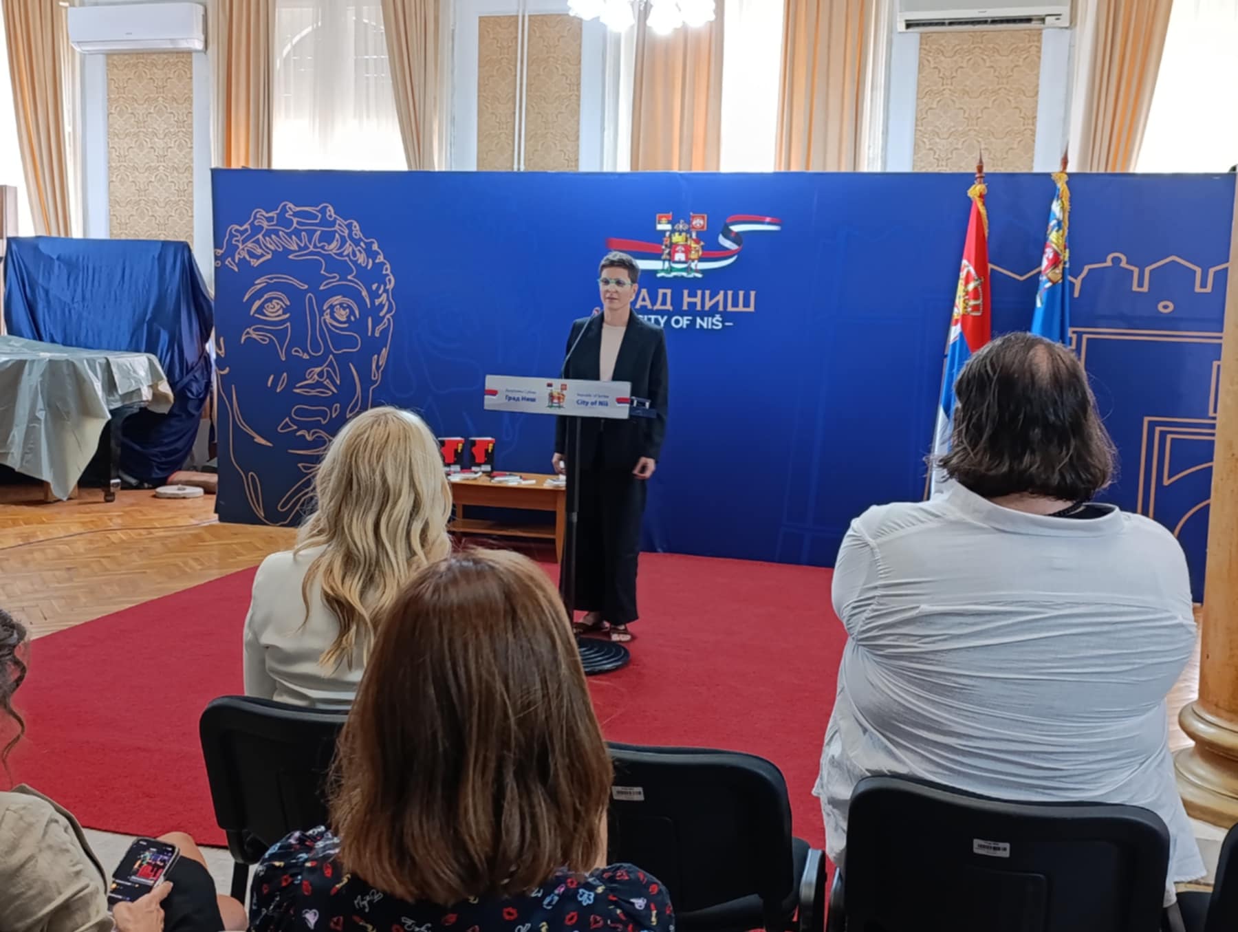 Društvo književnika i književnih prevodilaca Niša odlučilo je da dobitnica gradske književne nagrade „Slaviša Nikolin Živković” za 2024. godinu bude Lena Petrović za rukopis knjige priča „Bolje mesto”. Njoj je na današnjoj svečanosti u Gradskoj kući i uručena ta nagrada.Beograđanka, koja živi u Vašingtonu, pravnica po struci, ali i autorka već nekoliko poezijskih i proznih dela, istakla je da je ova nagrada inspiriše da i dalje nastavi sa pisanjem.
„Ova nagrada mi znači vetar u leđa. Kod umetnika, a verovatno i pisaca, uvek postoji ta sumnja da li je dobro to što rade, da li će dobiti neku afirmaciju za života i ova nagrada će me inspirisati da dalje radim ovo čime se bavim. Pošto ne živim u Srbiji, nego u Vašingtonu, znači mi i dodatno povezivanje sa Srbijom i književnom scenom u Srbiji i regionu”, navela je laureatkinja Lena Petrović.
Stručni žiri je odlučio da nagradi knjigu „Bolje mesto” zbog autorkinom izuzetnog književnog izraza i snažne poruke koju nosi njena zbirka priča. Žiri navodi da Lena Petrović s ogromnom dozom empatije poručuje da nade ipak ima, iako je čovek svuda prepušten sam sebi.
„Protagonisti ovih priča traže i emotivno bolje mesto, ali i geografsko pripadanje. Nekad shvate da je to nepripadanje zapravo olakšavajuće, a ne opterećujuće. Mislim da svi negde tražimo to bolje mesto, ali iako ga ne nađemo geografski, ono je nekad u nama”, dodala je autorka.
Njoj je nagradu uručila članica gradskog veća Ivana Cvetković.
„Ova svečanost već osam godina zaredom je više od kulturnog događaja. Ona je znak da Niš, kao grad sa dubokim književnim korenima, neguje reč kao vrednost, a stvaralaštvo kao trajno nasleđe. Gradska književna nagrada, koja nosi ime Slaviše Nikolina Živkovića, nije samo priznanje za jedan rukopis, ona je podsećanje na vrednost koje kao grad želimo da čuvamo i negujemo”, poručila je gradska većnica.
Predsednik Društva književnika i književnih prevodilaca Niša Dalibor Popović Pop naveo je da će deveti konkurs biti raspisan 1. oktobra, a trajaće do 30. decembra.
Lena Petrović